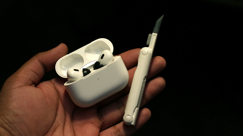 Person holding a pair of AirPods and a cleaning kit