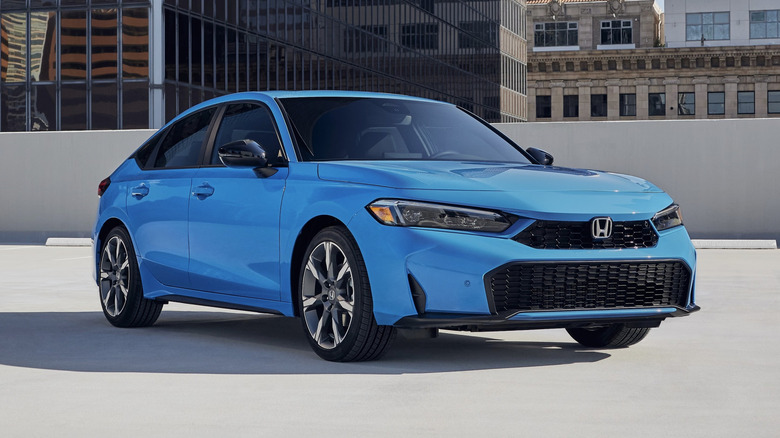 blue 2026 Honda Civic Sport Touring Hybrid hatchback parked on top of a parking garage in a city