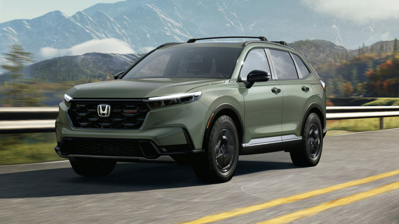 A green 2027 Honda CR-V driving on a mountain road