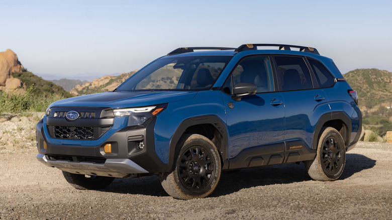 A blue hybrid Subaru Forester parked on gravel