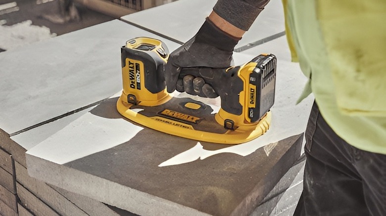 Construction worker using DeWalt GRABO on concrete tile
