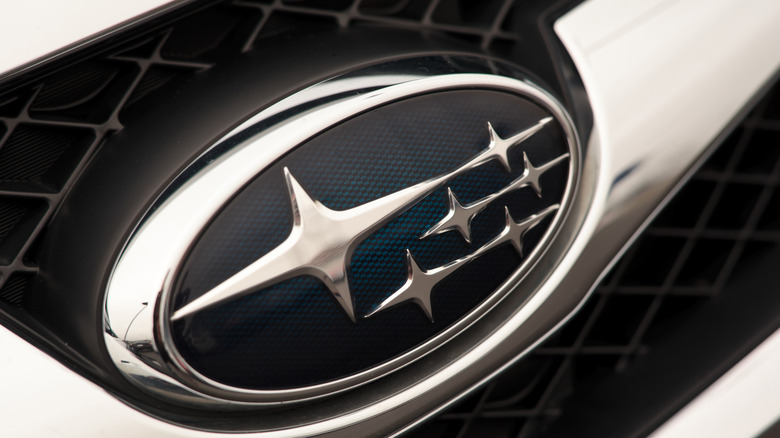 A close-up of a Subaru badge on a light-colored vehicle