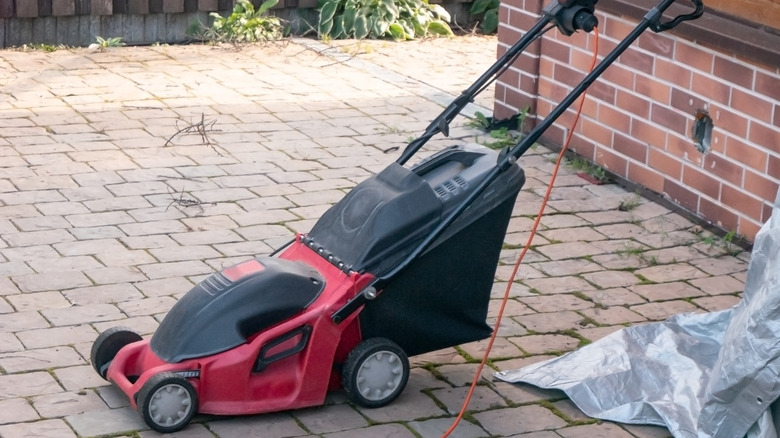 A corded lawn mower on a pathway.