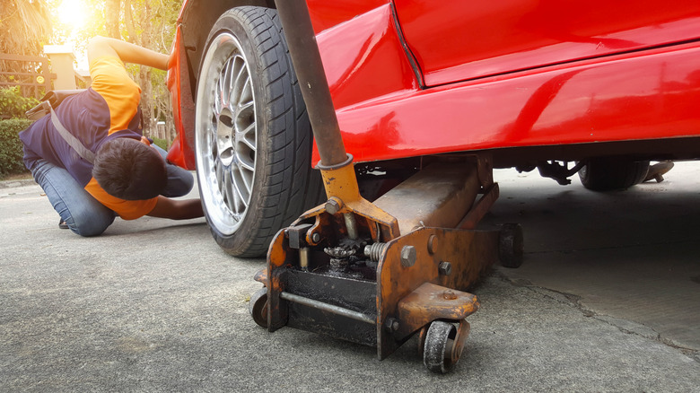 Person using floor jack on their car