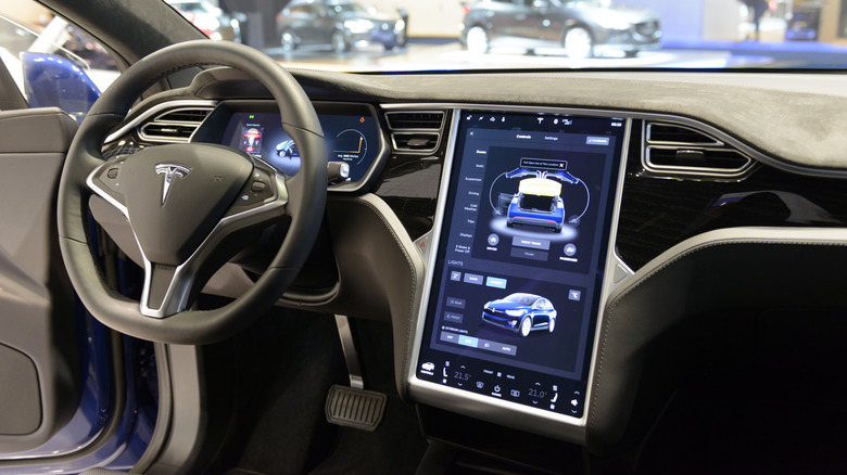 The interior of a Tesla with a large vertical touchscreen and no physical buttons or knobs