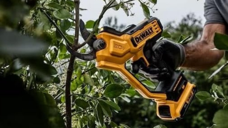 A person using a DeWalt 20-volt cordless pruner