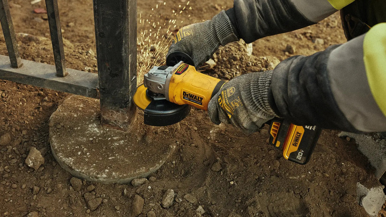 DeWalt 20V Max angle grinder cutting through a metal post