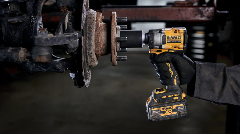 A DeWalt 20V Max Atomic impact wrench being used on a vehicle wheel rim