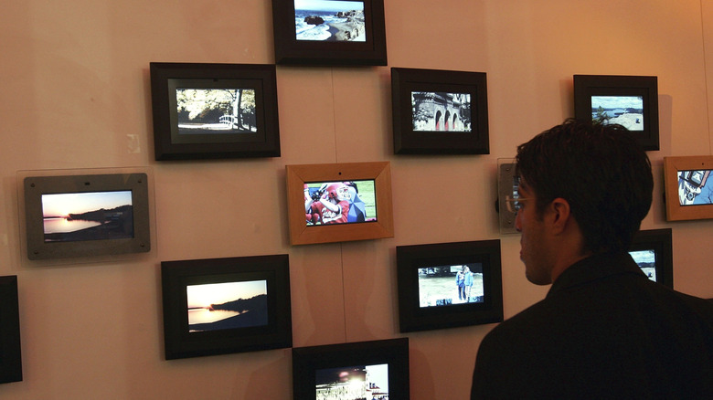 A person looking at digital picture frames on display on a wall