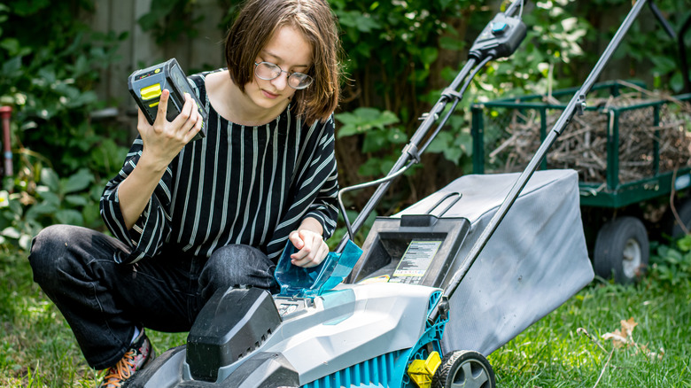 Person replaces a component of a lawn mower.