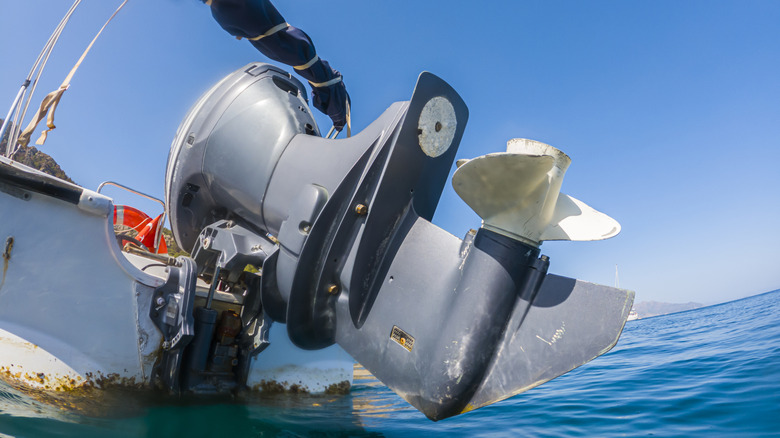 Gray outboard boat motor with raised propeller above seawater