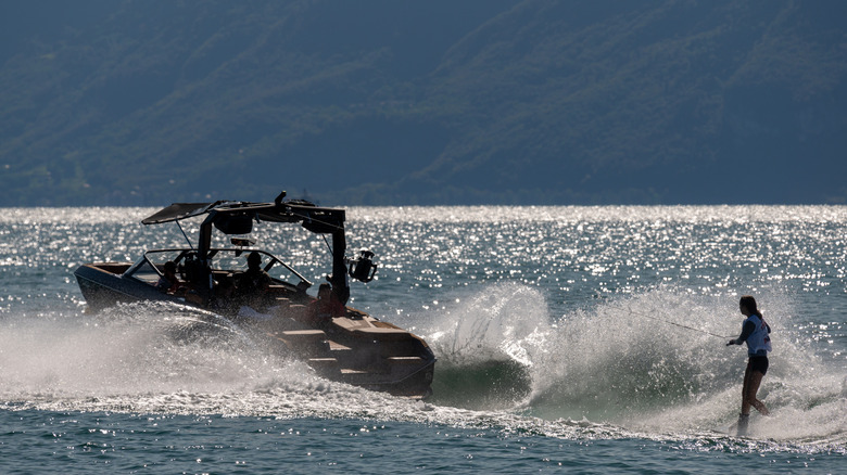 Person wakeboarding behind a motorboat on sparkling water
