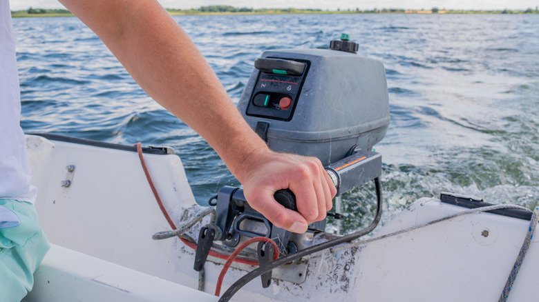 Person gripping the handle of an outboard boat motor