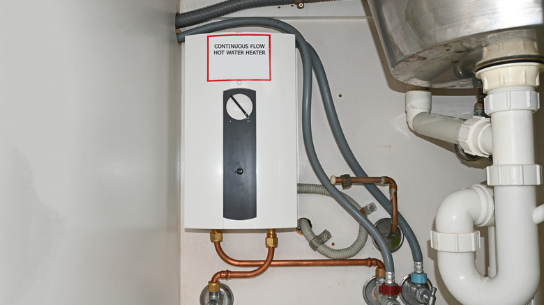 A tankless hot water system installed under a sink.