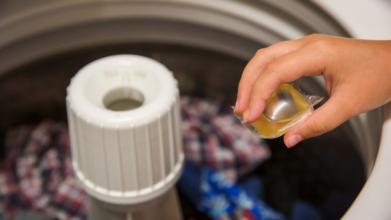 A person putting a laundry pod in a washer.