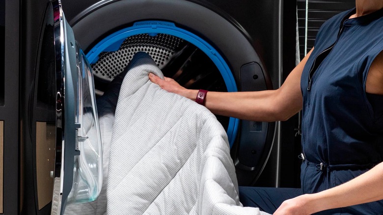 A person pulling laundry from a washing machine.