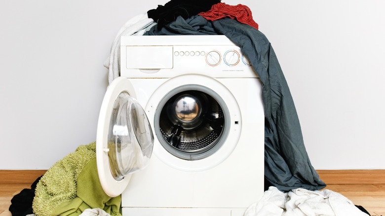 A washer-dryer combo covered in clothes.