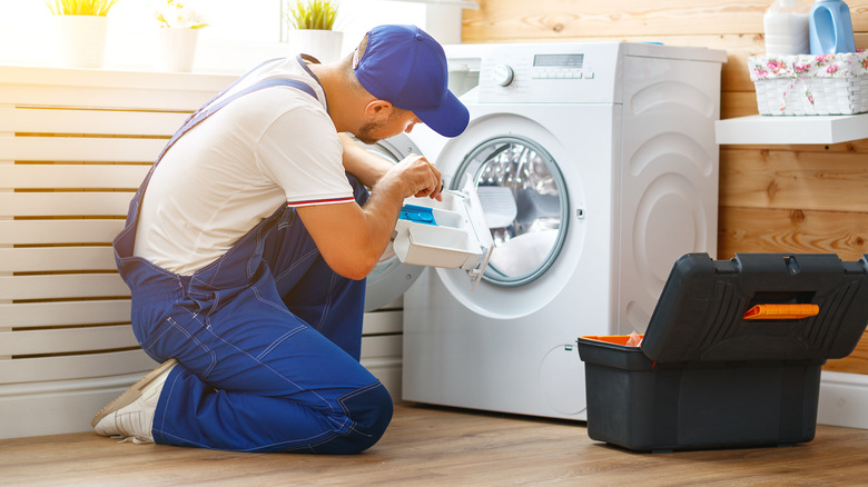 A person repairing a washing machine.