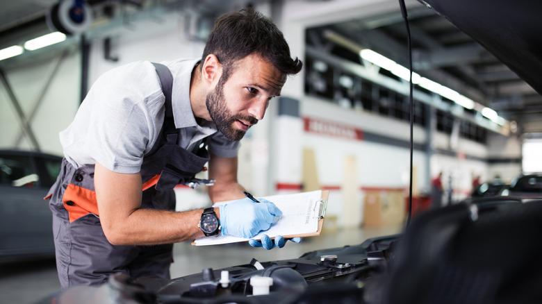 Auto mechanic checking car engine.