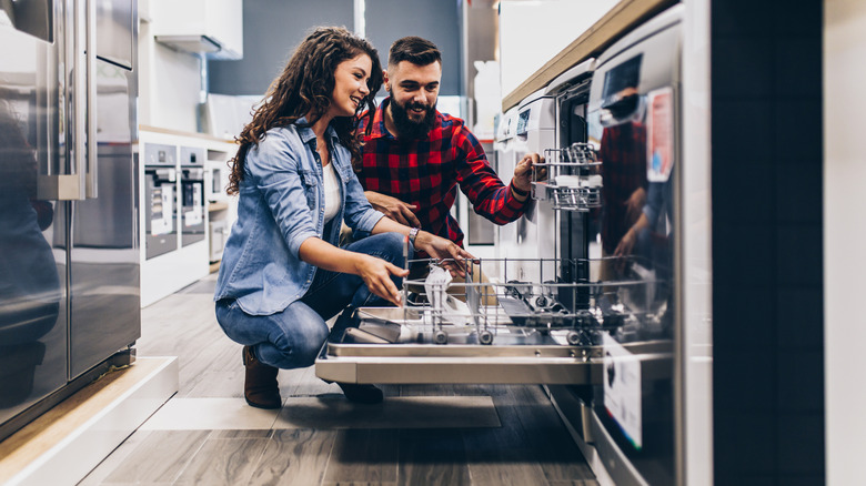 couple looking at a dishwasher inside an appliance store