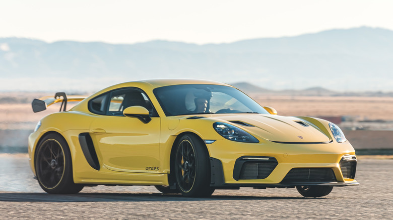 Front 3/4 view of Porsche Cayman GT4 RS sliding in trackside setting