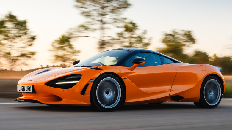Front 3/4 view of McLaren 750S driving on road in forested setting