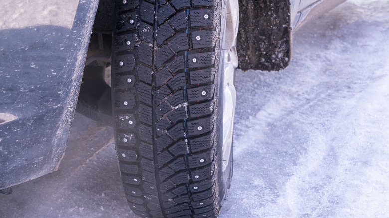Studded tires on vehicle atop icy roadway.