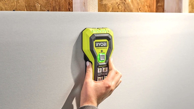 Person using AAA battery powered Ryobi Whole Stud Detector