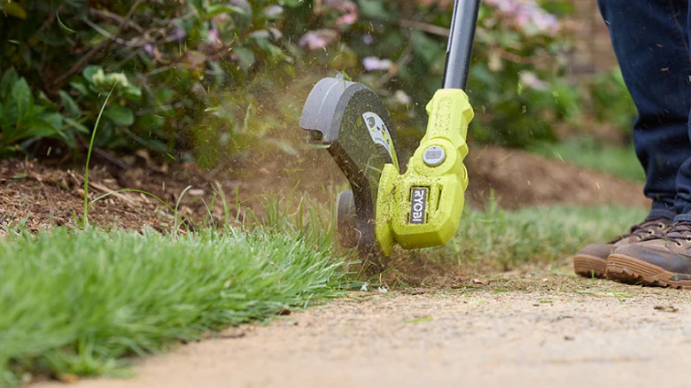 Close-up of the blade of a Ryobi 18V ONE+ 13-inch string trimmer cutting grass