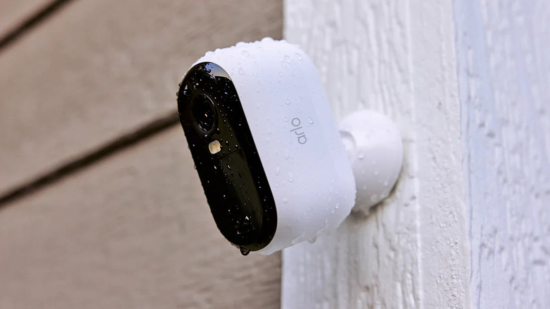 Arlo security camera mounted outdoors with water droplets on it.