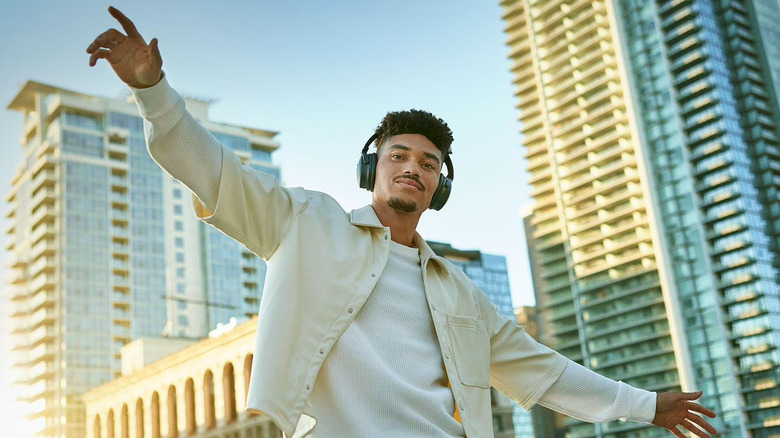 A man wearing a pair of Bose QuietComfort headphones, with a cityscape in the background.