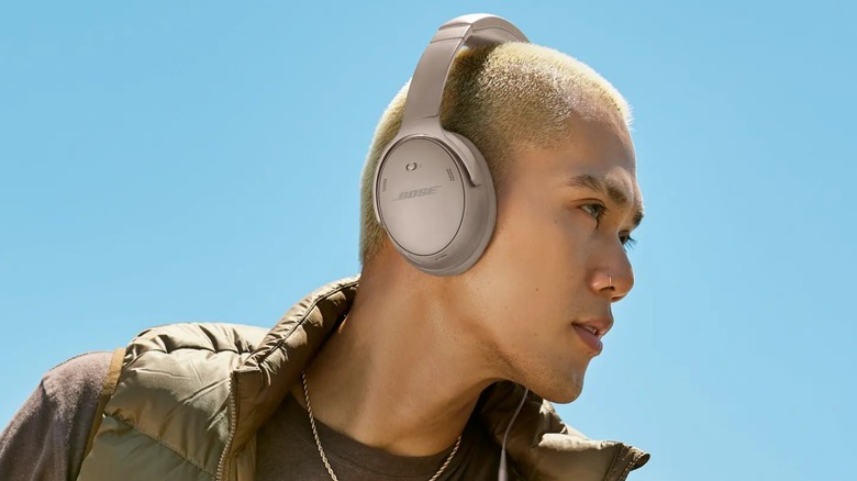 Man wearing Bose QuietComfort headphones against a clear blue sky.