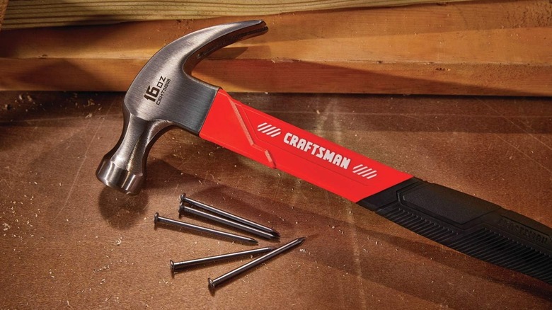 Craftsman hammer and nails on a wooden surface