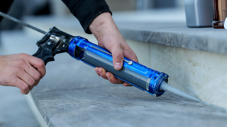 A person using a caulk gun outside.
