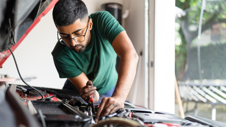 A home mechanic working on a car engine