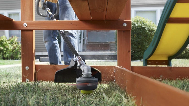 A person using a gas powered Ryobi string trimmer