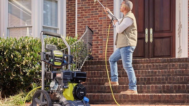 A person using a gas powered Ryobi pressure washer