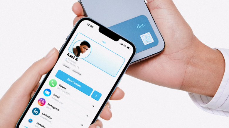Hand holding phone with Dot. digital business card while another phone taps it.