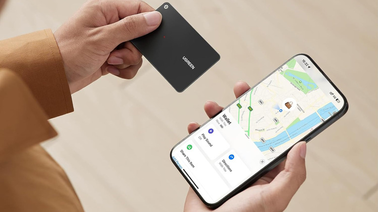 A Ugreen wallet tracker held next to a smartphone.