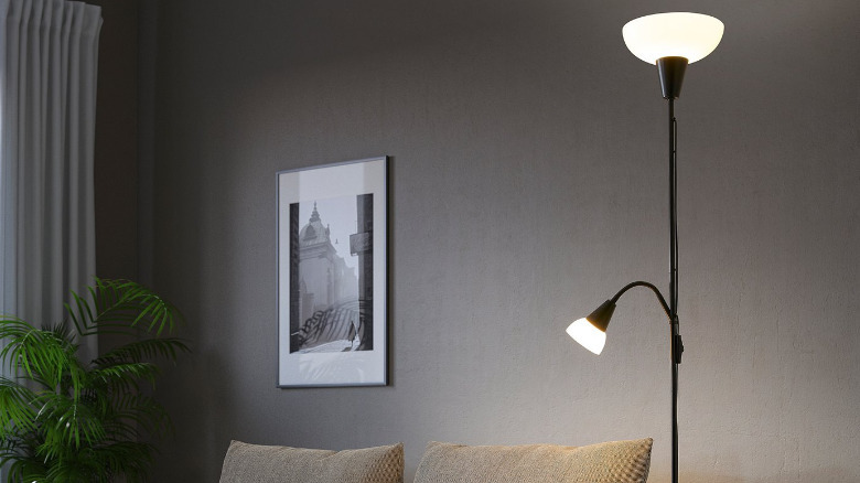 The TÅGARP floor lamp with the lights on, in a living room.