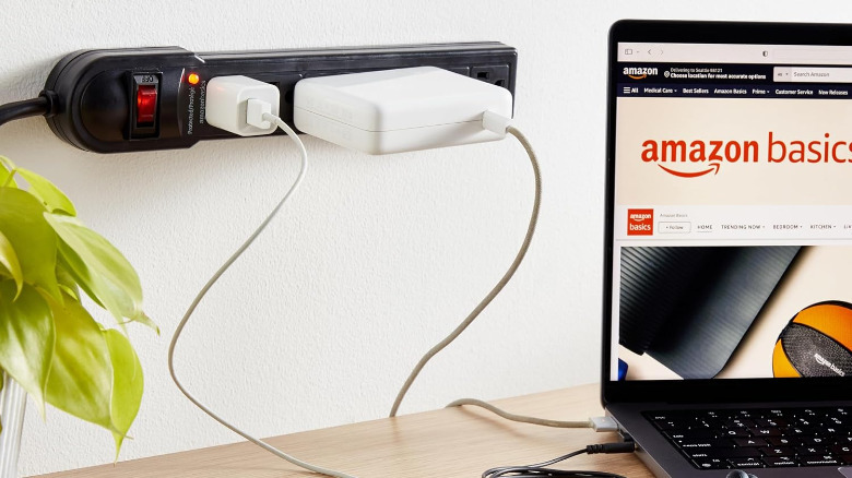 An Amazon Basics power strip monted on the wall next to a PC on a table.
