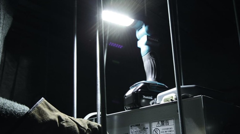 A Makita light above someone working on HVAC.
