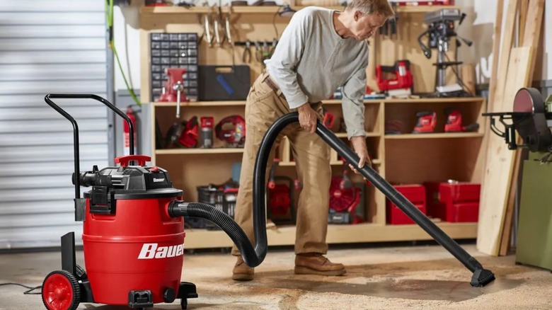 A person using a Harbor Freight Bauer wet-dry shop vacuum