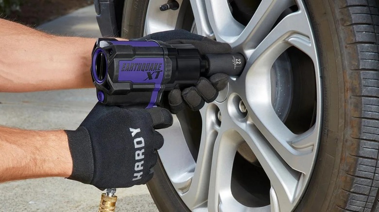 A person using a Harbor Freight earthquake xt impact wrench to remove a car's lugnuts
