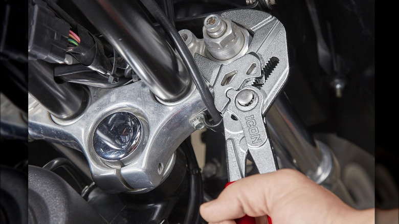 The Icon 10-inch Pliers Wrench used on an engine.