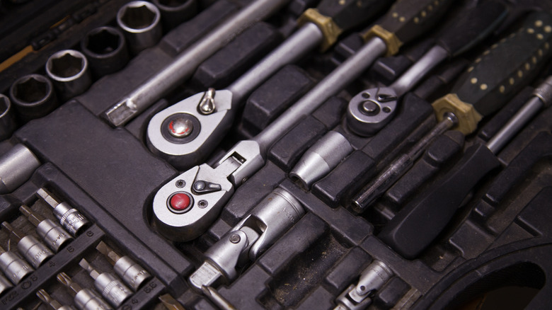 A close-up of several ratchets and attachments inside a tool box