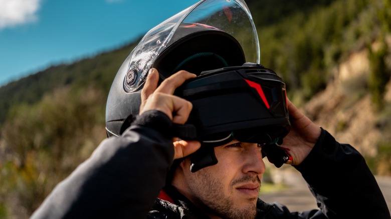 A rider donning a full face motorcycle helmet before a ride.