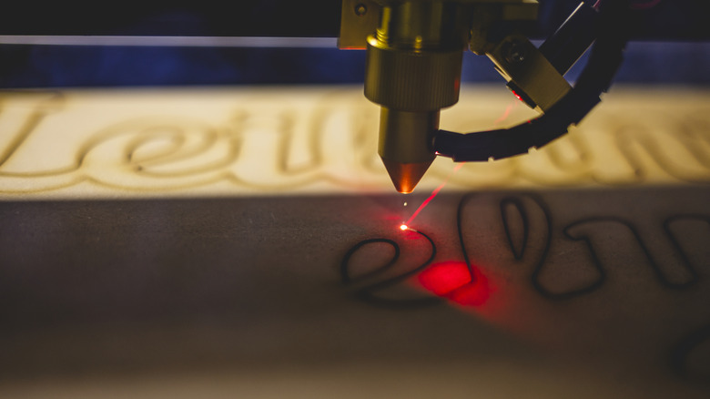 Laser engraving machine etching cursive lettering onto a dark surface