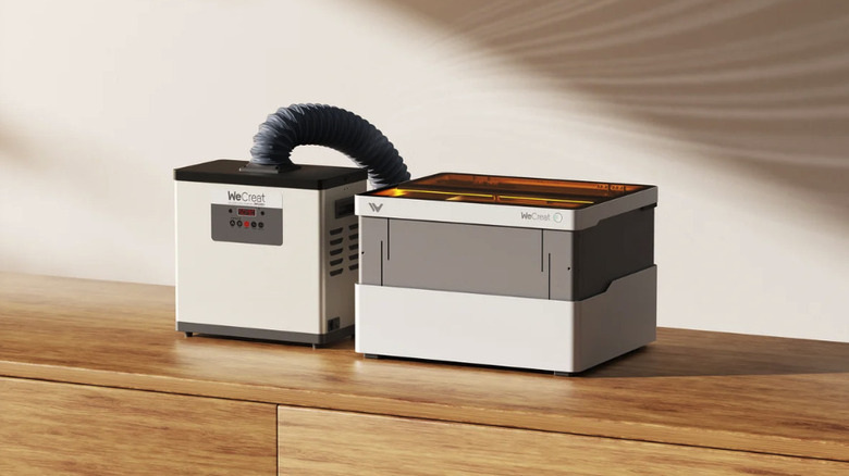 The WeCreat laser engraver connected to an exhaust filter by a flexible hose