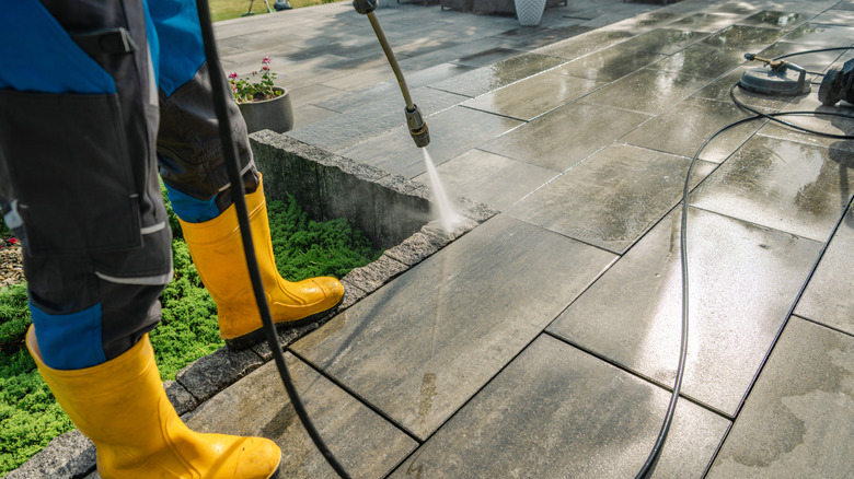person using pressure washer to clean outdoor tile